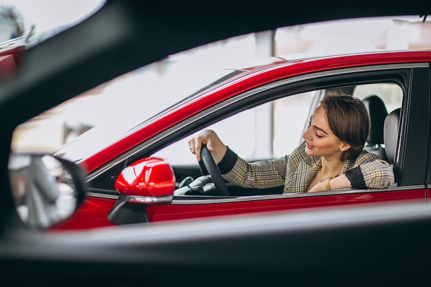 Mujer sentada i coche en un coche showrrom