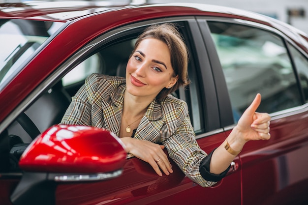 Mujer sentada i coche en un coche showrrom