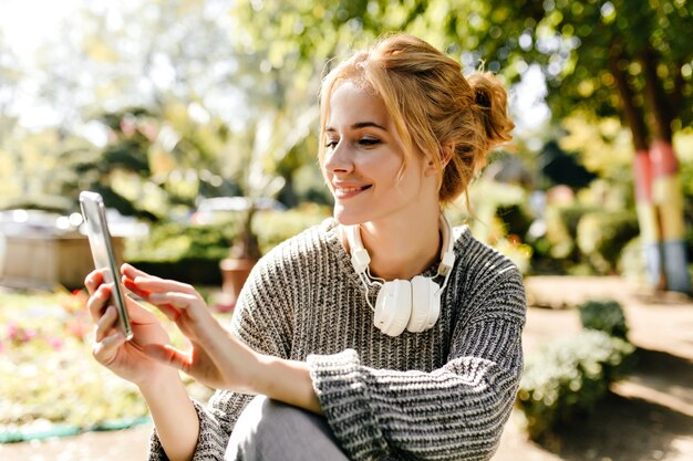 mujer sentada en invernadero toma selfie en su teléfono