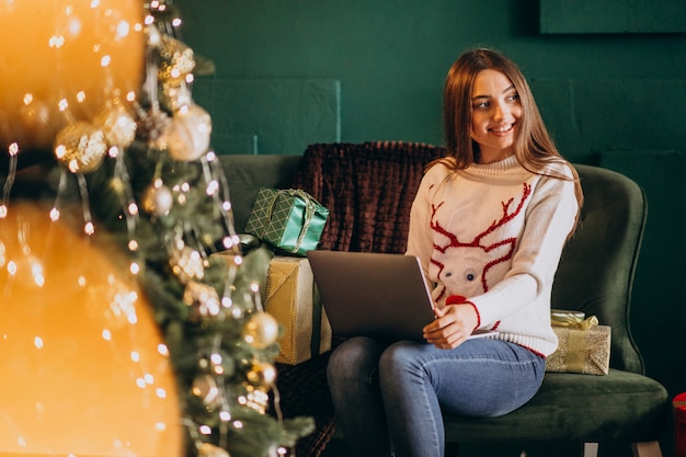 Mujer sentada junto al árbol de Navidad y compras en línea de ventas