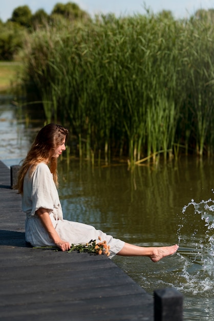 Mujer sentada junto al lago tiro completo