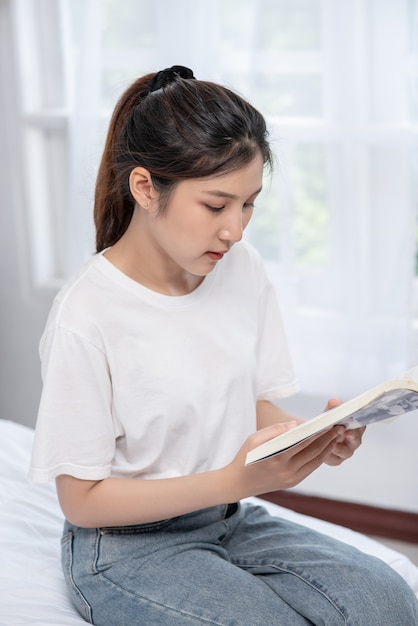 Una mujer sentada y leyendo un dormitorio.