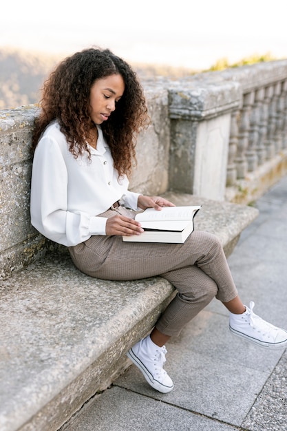 Foto gratuita mujer sentada y leyendo un libro