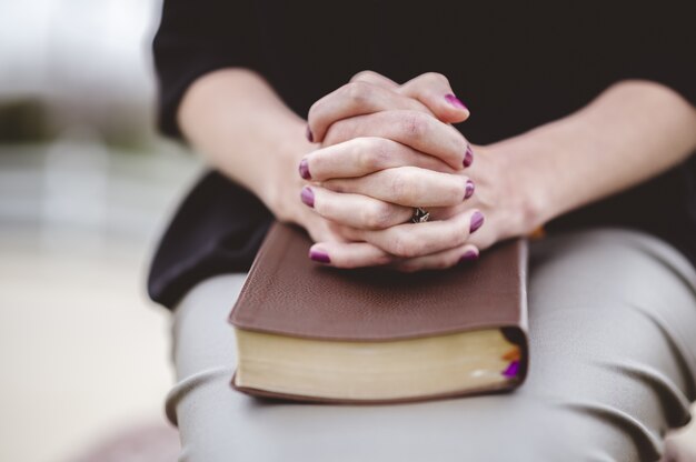 Mujer sentada con la mano en el libro en su regazo