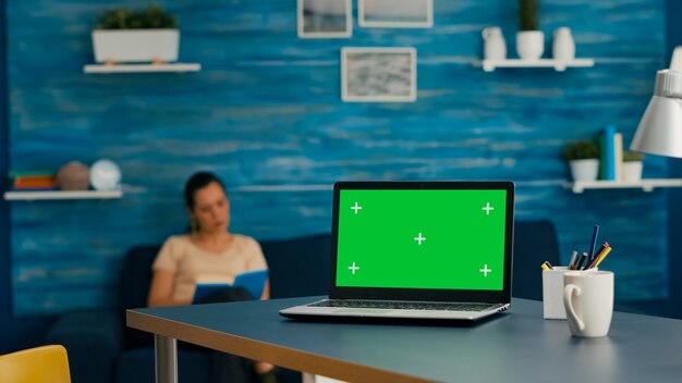 Mujer sentada en la mesa de escritorio trabajando en el comercio de negocios usando una computadora portátil aislada con simulacros de clave de croma de pantalla verde. Mujer caucásica escribiendo en pc en estudio de oficina en casa