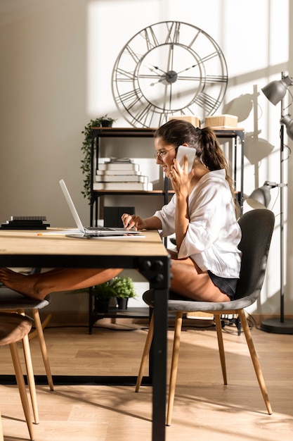 Foto gratuita mujer sentada a la mesa hablando por teléfono