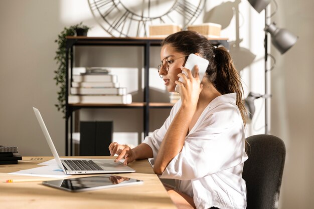 Mujer sentada a la mesa hablando por teléfono