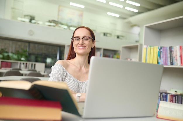 Mujer sentada en la mesa con una laptop mirando a la cámara