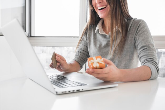 Mujer sentada a la mesa con laptop y tarjeta de crédito