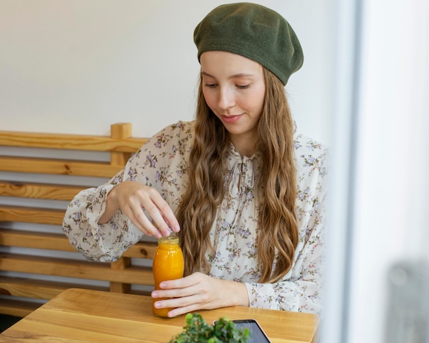 Mujer sentada a la mesa sosteniendo una botella de jugo fresco