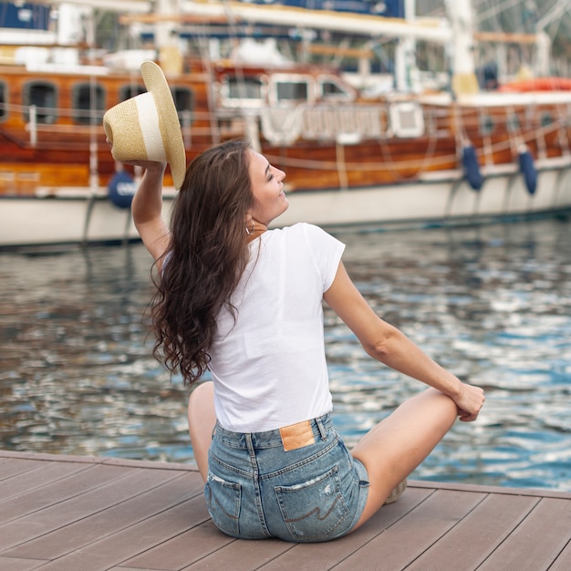 Foto gratuita mujer sentada en la orilla de un puerto