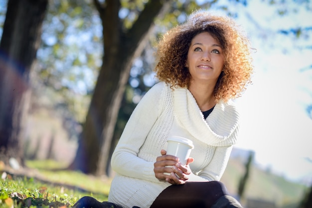 Mujer sentada en el parque con un vaso de café