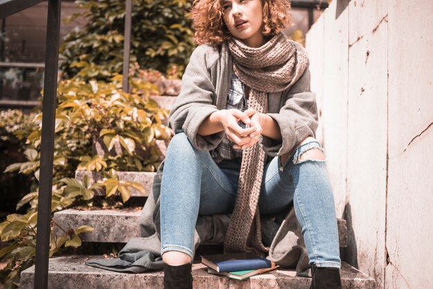 Mujer sentada en pasos cerca de libros