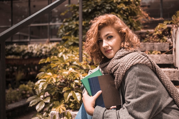 Mujer sentada en pasos y sosteniendo libros