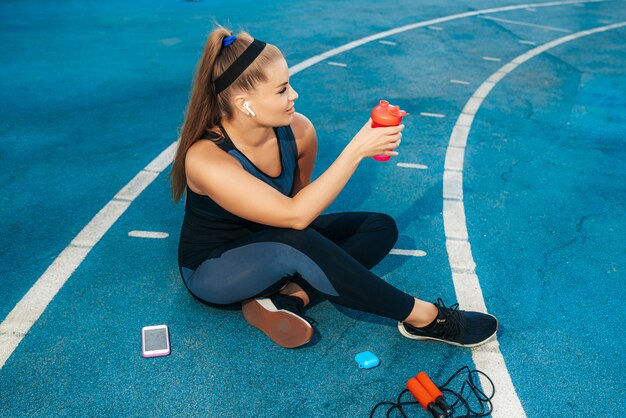 Mujer sentada en el patio de recreo con una botella de agua