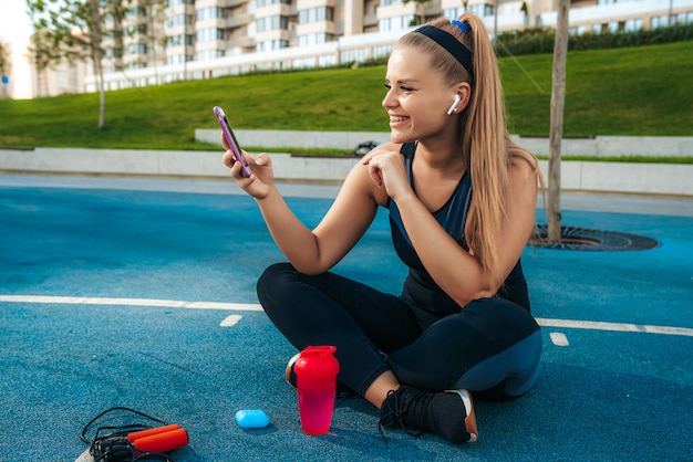 Foto gratuita mujer sentada en el patio de recreo con un teléfono en sus manos