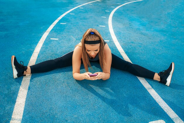 Foto gratuita mujer sentada en el patio de recreo con un teléfono en sus manos