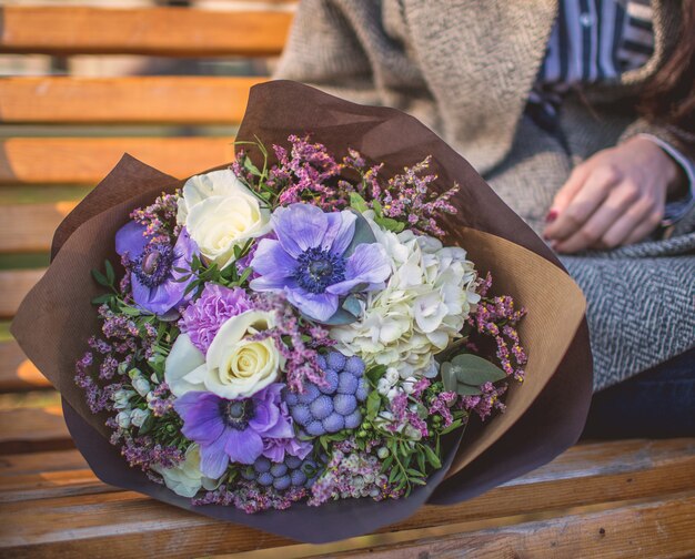 Mujer sentada en el pench con un ramo de flores de papel.