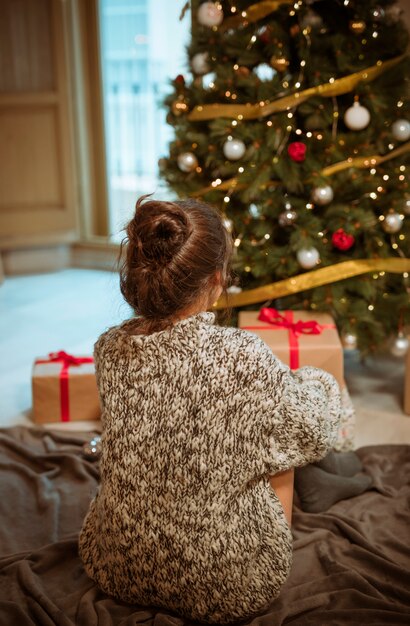 Mujer sentada en el piso cerca del árbol de navidad