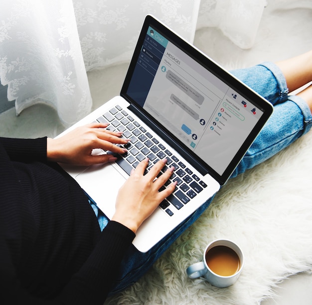 Foto gratuita una mujer sentada en el piso y usando una computadora portátil