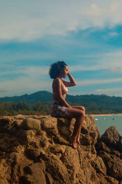 Mujer sentada en la playa disfrutando del impresionante amanecer