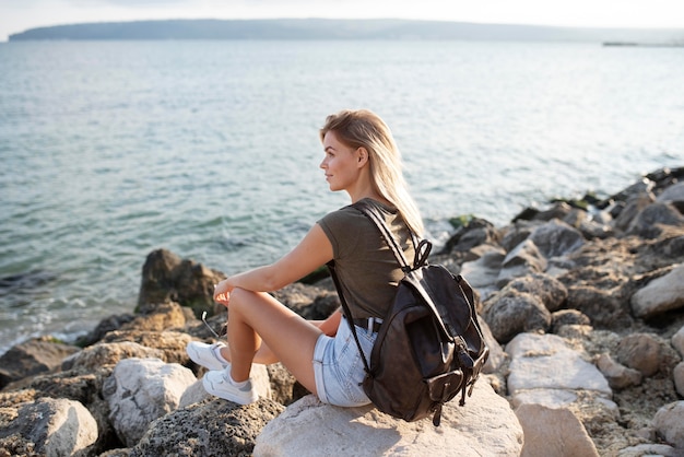 Mujer sentada en la playa de tiro completo