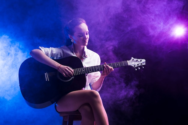 Mujer sentada en la posición clásica para tocar la guitarra