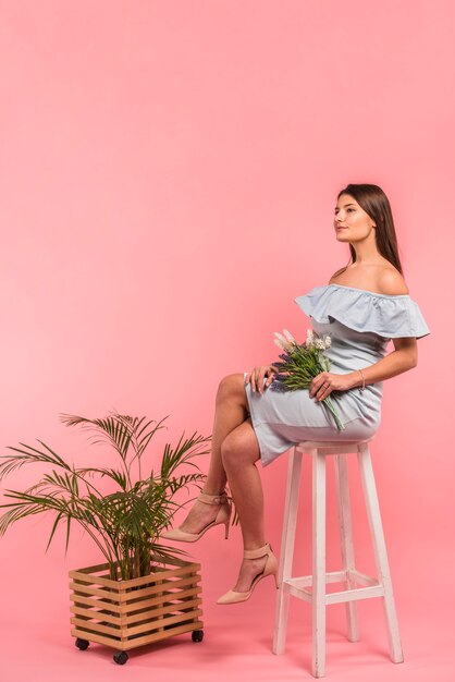 Mujer sentada con ramo de flores en silla