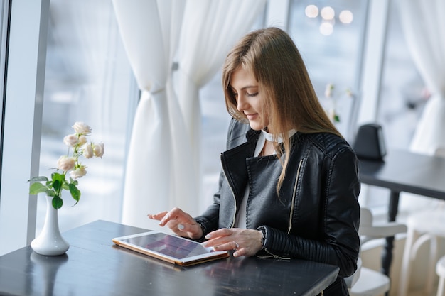 Mujer sentada en un restaurante tocando una tablet