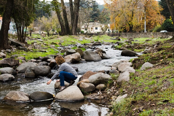 Foto gratuito mujer sentada en las rocas junto al río