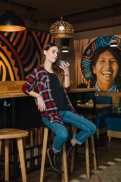 Foto gratuita mujer sentada en silla de bar con café en café