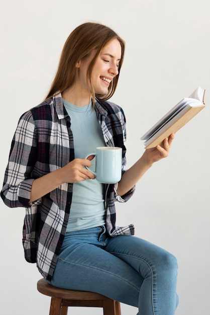 Foto gratuita mujer sentada en una silla mientras lee un libro