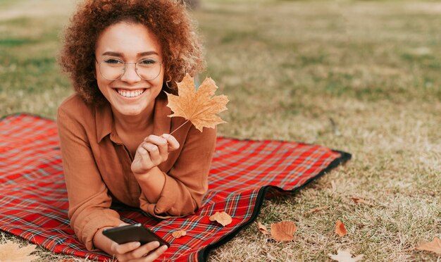 Mujer sentada sobre una manta con espacio de copia en otoño