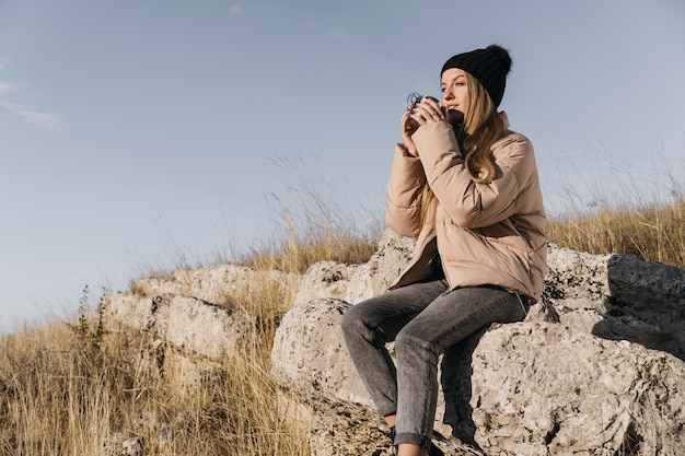 Mujer sentada sobre rocas con taza