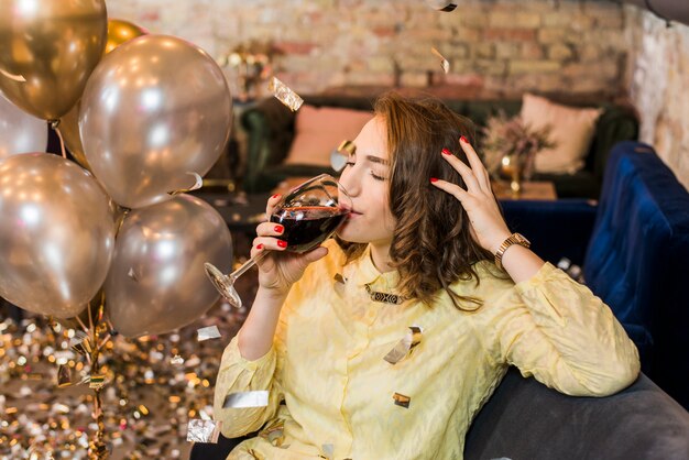 Mujer sentada en el sofá bebiendo vino en la celebración del partido