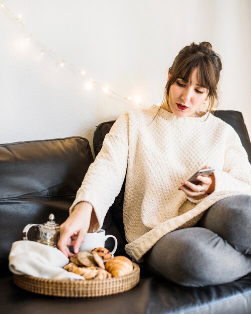 Mujer sentada en el sofá comiendo su desayuno