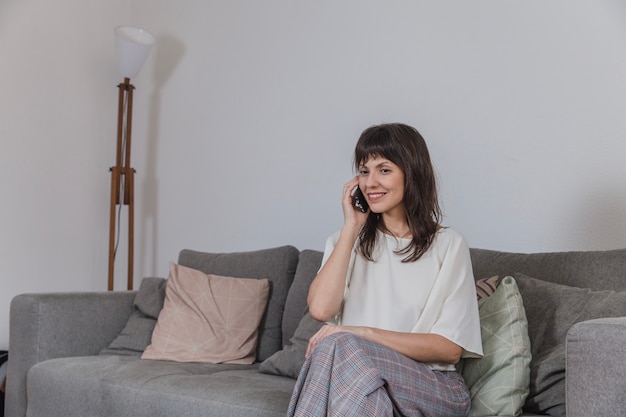 Foto gratuita mujer sentada en sofá y hablando por teléfono