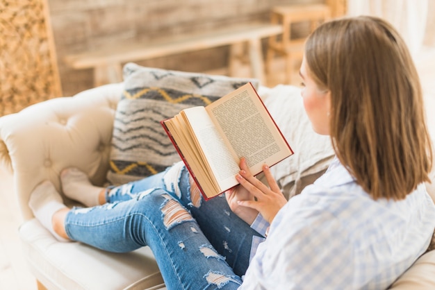Mujer sentada en el sofá con el libro de lectura