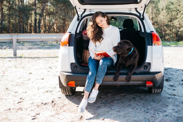 Mujer sentada con su perro en maletero abierto