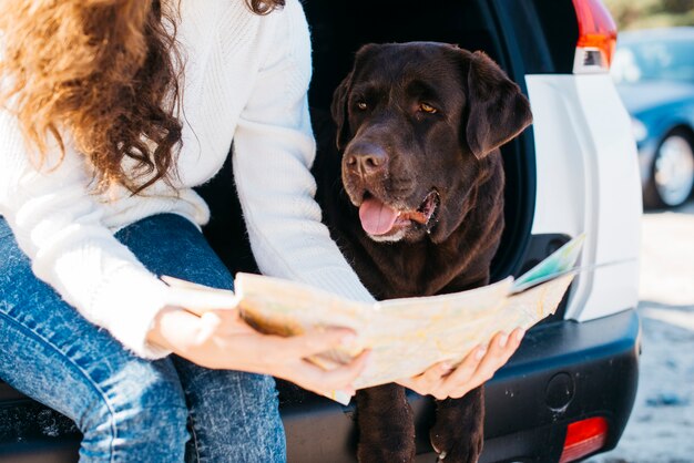 Mujer sentada con su perro en maletero abierto