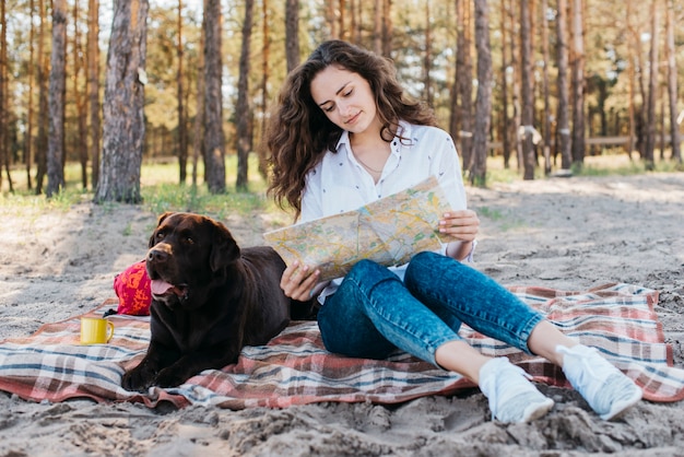 Foto gratuita mujer sentada con su perro en la naturaleza