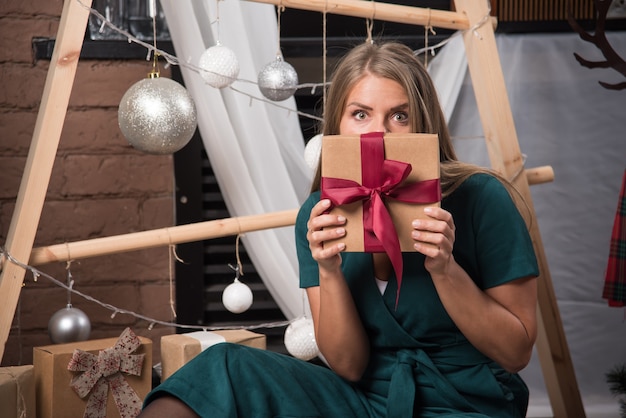 Mujer sentada en el suelo en casa con regalos de Navidad