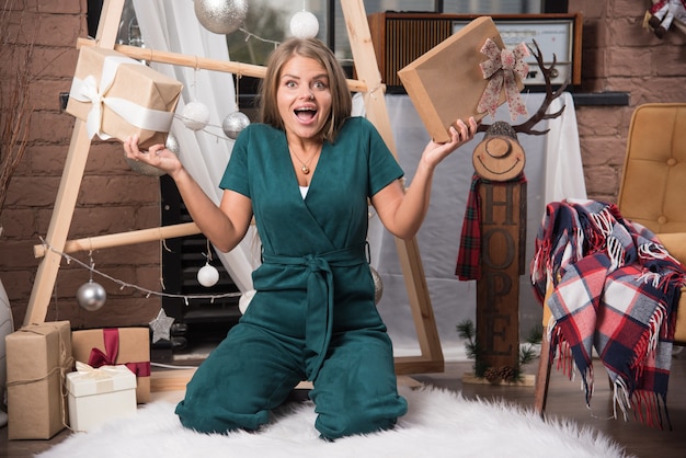 Mujer sentada en el suelo en casa con regalos de Navidad