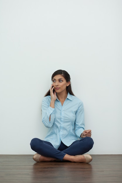 Foto gratuita mujer sentada en el suelo y llamando por teléfono