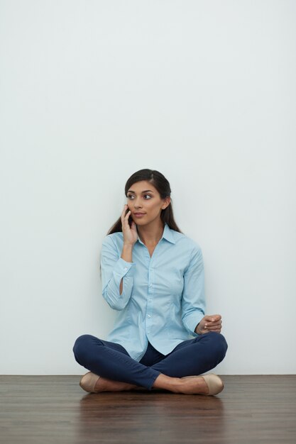 Mujer sentada en el suelo y llamando por teléfono