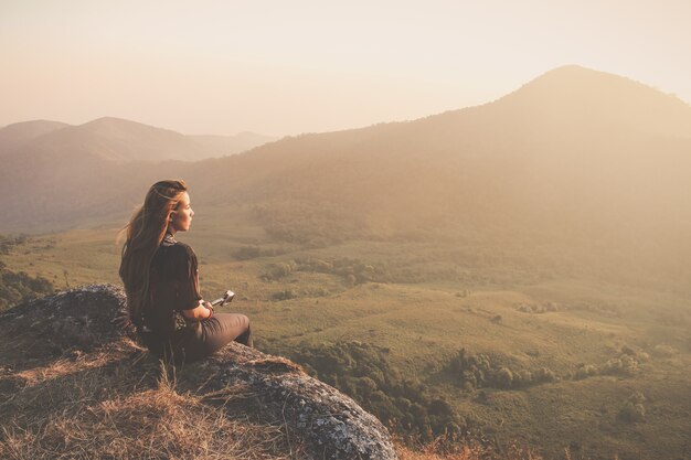 Mujer sentada en el suelo mirando al atardecer