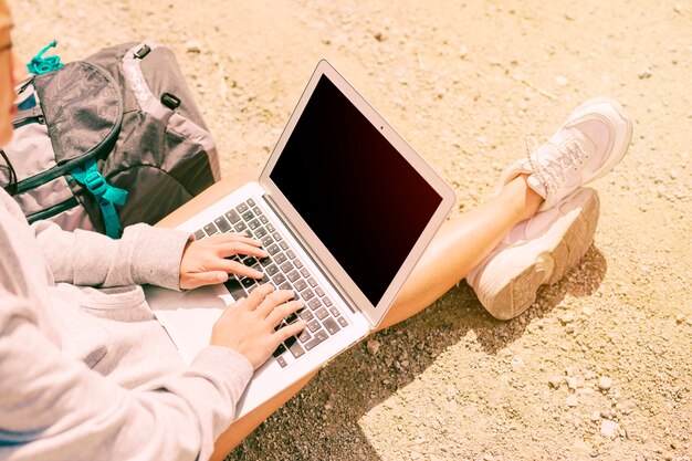 Mujer sentada en el suelo y trabajando en laptop