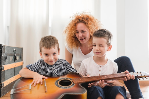 Mujer sentada con sus hijos tocando la guitarra