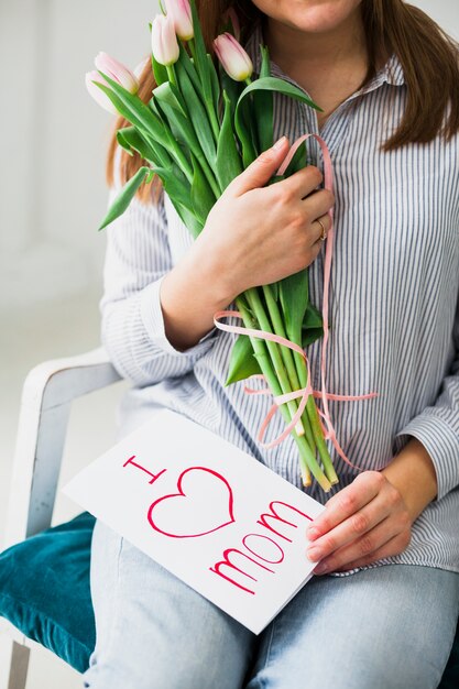 Mujer sentada con tarjeta de felicitación con la inscripción &quot;Amo a mamá&quot;