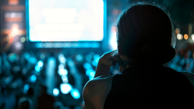 Mujer sentada viendo fútbol en un lugar público por la noche